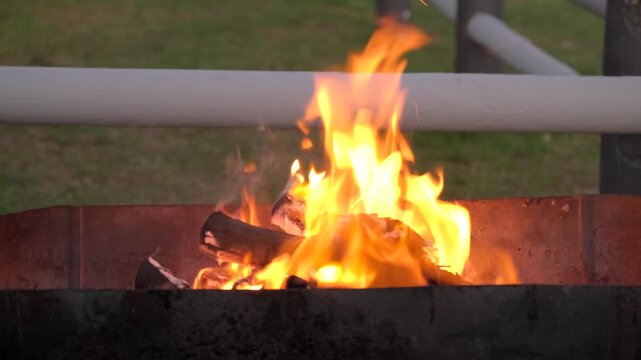 Placing braai grid on open wood fire with hot yellow flames to burn it clean