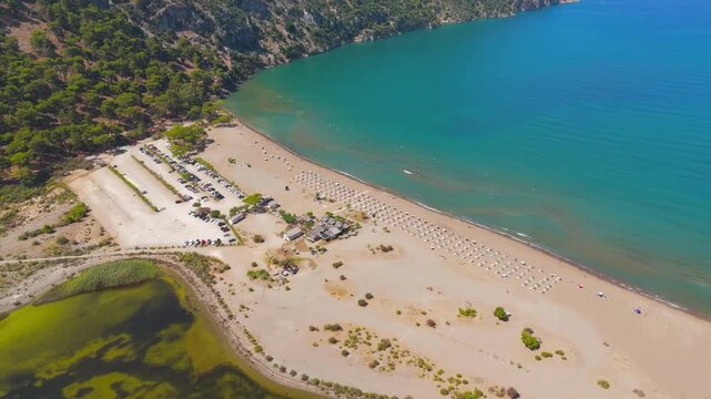 Dalyan, Turkey. Iztuzu Beach, a 4.5 km sandy spit between the Dalyan River delta and the turquoise Mediterranean, aerial drone view over sun loungers and shoreline cafe on a bright summer day. Aerial