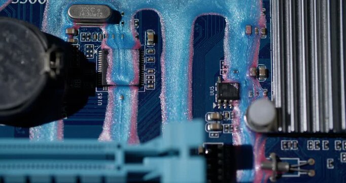Motherboard art. Flowing glitter dye. Pink blue shimmering paint stream on hardware scheme. Color blur abstract equipment background.