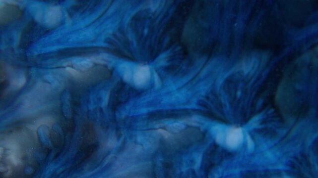 Blur ink blob. Pigment spread. Blue sparkling watercolor dye blotch on gray black acrylic. Abstract wavy color mix prism background.