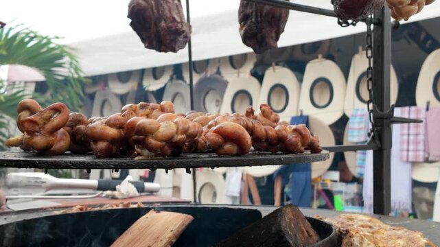 Grilling meat at circular barbecue dinner party in street food market outside - Roasted pork intestines meat on charcoal grill for family backyard gathering - Food and summer activities