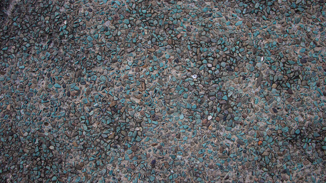 Top view of pebble wash texture with turquoise and grey stones background