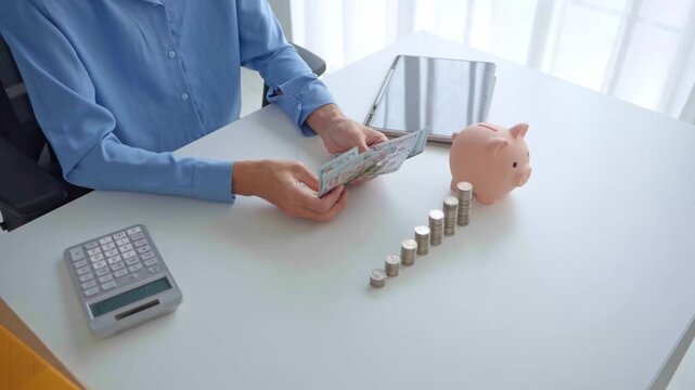 Asian businessman counting banknote with stacking coin and piggy bank on table investment concept.