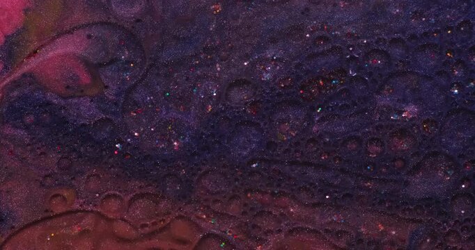 Glitter ink. Oil bubbles. Defocused pink purple blue colorful bright sequins round texture floating on abstract acrylic art background.