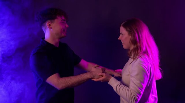 A couple s love and fun concept, with a young man and woman dancing and holding hands in a club setting. The scene is illuminated by vibrant neon lights and smoke, creating a moody and energetic atmos