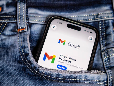 Smartphone displaying gmail app update screen in a jeans pocket isolated on white background
