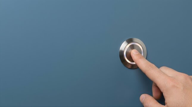 Finger pressing a modern brushed metal push button on a dark blue wall surface concept