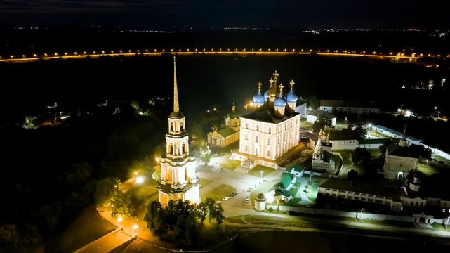 Ryazan, Russia. Ryazan Kremlin, the Cathedral of the Assumption and its 86-metre neoclassical bell tower with a gold-coated spire, aerial night view with dramatic illumination over the Oka River. Dro