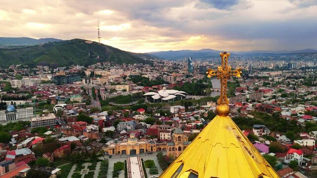 Aerial Flight Orbit Golden Cross Holy Trinity Cathedral Sameba and Cityscape Tbilisi Georgia
