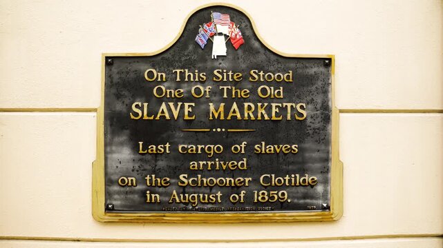 A steady shot captures a historical marker in Mobile, Alabama, referencing the arrival of the schooner Clotilde and the last known illegal slave shipment into the United States.