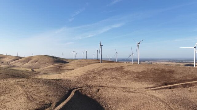 Drone aerial footage showcasing the expansive wind farm at Altamont Pass, with turbines spinning against a clear blue sky, highlighting sustainable and clean energy production in California