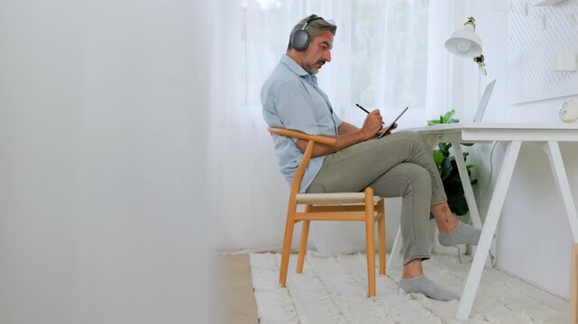 Mature businessman using tablet and stylus while working in modern home office.