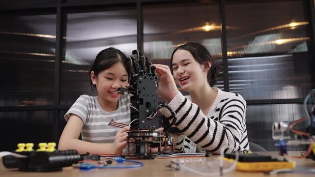 Student girls learning robotics and STEM engineering through hands-on experiments with robotic arms.