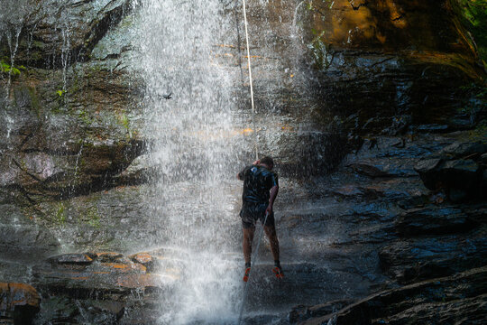 Silhouette of a person abseiling down waterfall