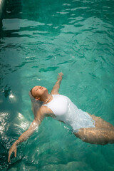 Fototapeta premium Woman floats in a pool enjoying warm weather in Bali