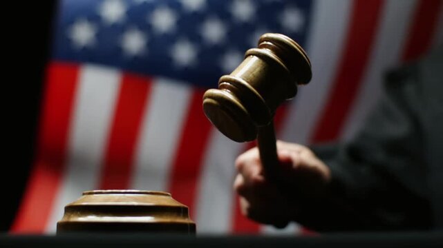 Judge Holding Wooden Gavel Against American Flag In Court