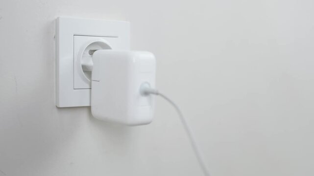 Male Hand Plugging and Unplugging Charger in Wall Socket Closeup