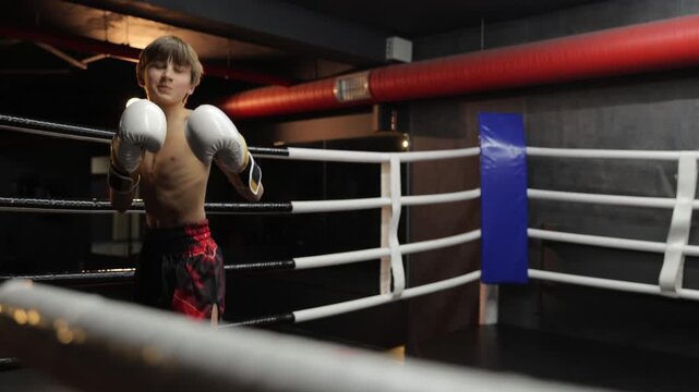 Young boy boxer training punches in a boxing ring