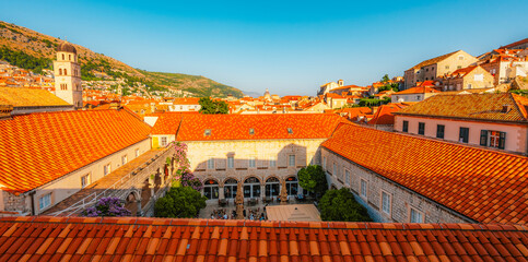 Naklejka premium Golden hour panorama of Dubrovnik's historic fortifications and old port at dusk, featuring sunlight on ancient stone walls and Mediterranean architecture in Croatia
