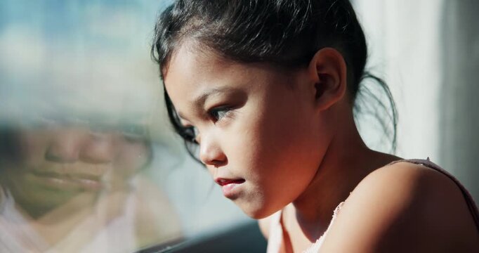 Sad, girl and thinking with window for trauma, mental health or anxiety on glass in home. Thoughtful, kid or child with depression, reflection or regret for outdoor fear, crisis or bullying in house