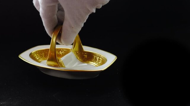 Gloved hands present gold plated tableware against a black background, evoking exclusivity, prestige, and high-end hospitality. Ideal for luxury branding, fine dining, and premium lifestyle storytelli