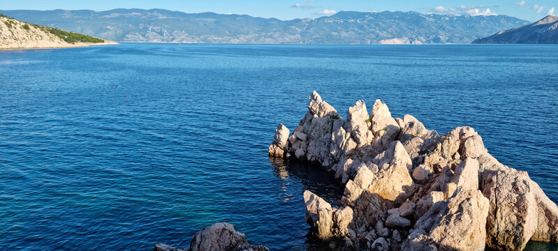 Scenic view of sharp limestone rocks rising from the blue sea on the western shore of Bunculuka cove in Baska on Krk island Croatia.