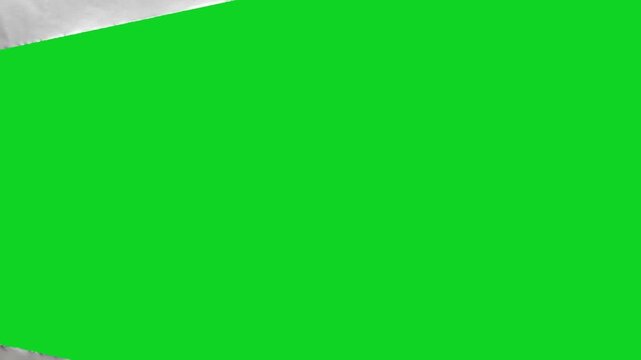 Torn crumpled white grunge paper rip revealing animated on a green screen chroma key background. It gives a high quality professional template design element for video compositing motion