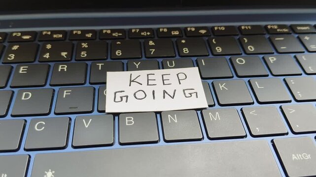 Keep going word Handwritten on white paper placed on top of personal laptop computer keyboard. Work, job and business motivation or inspiration slogan concept. Encouragement to achieve goal or success