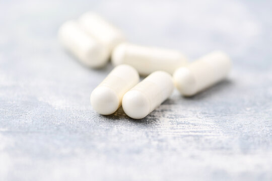 Creatine capsules on bright wooden background. Soft focus. Close up. Copy space.