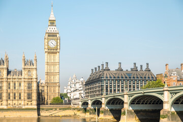 Obraz premium An iconic view of the Elizabeth Tower, commonly known as Big Ben, stands prominently alongside the Palace of Westminster and Westminster Bridge overlooking the River Thames in London.