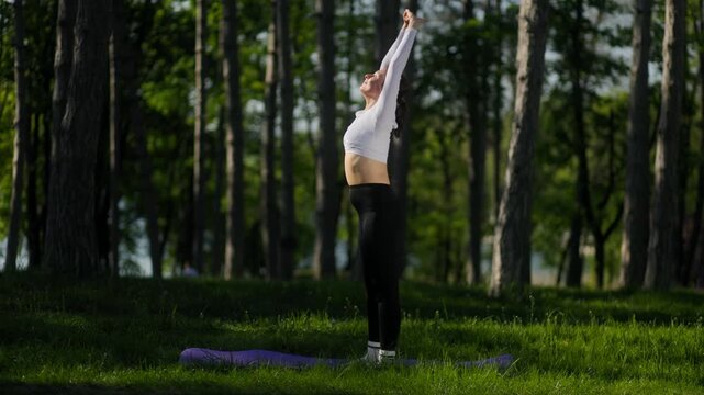 45 year old woman doing sun salutation flow in outdoor fitness session