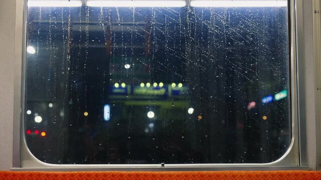 Rainy window view inside moving train during night journey.