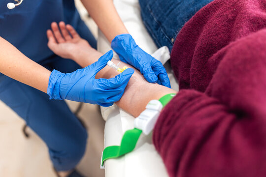Nurse inserting IV cannula needle into patient arm for blood test or infusion. Medical procedure, hospital treatment, healthcare, blood donation, clinic checkup and laboratory analysis concept.