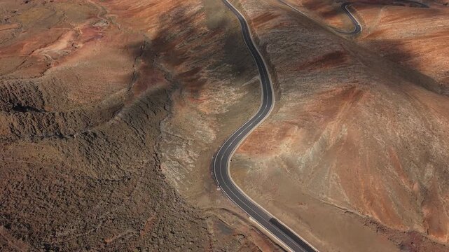 Aerial view of The Betancuria Rural Park, which is a Spanish protected natural area located in the Canary Islands. Drone POV exploration of Fuerteventura Island. View of serpentine road.