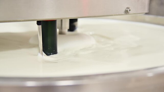 Mixing milk in industrial machine for cheese production process in dairy facility