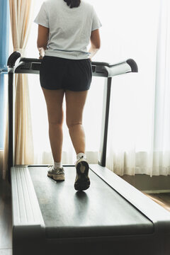 Active woman walking on a treadmill at home gym.