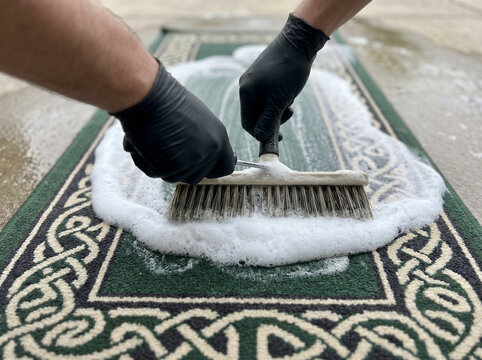 Celtic-knot pattern wool runner rug short-handle roller brush pushing thick wave of shampoo foam along the narrow weave