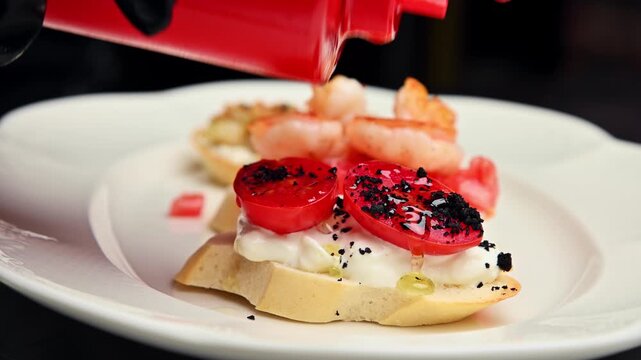 Squeezing ketchup onto bruschetta with shrimp and tomato on a white plate