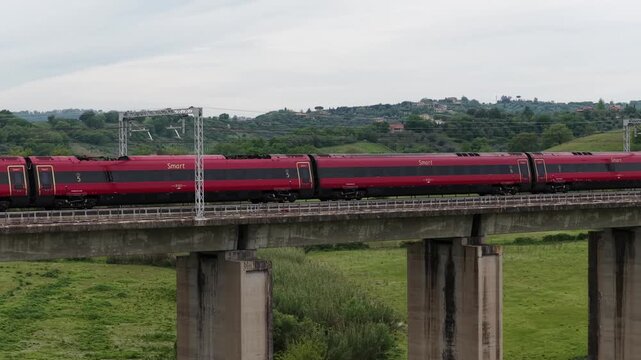 Treno ad alta velocit&agrave; attraversa un ponte e entra in una galleria. Italia.
Vista aerea di un treno tra le campagne romane.