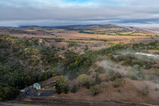 Aerial view of the Glenbawn Dam valve house with surrounding landscape in NSW Australia. Drone photograph captures the water management infrastructure, reservoir waters and rugged scenery