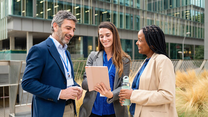 Fototapeta premium Diverse business people collaborating using digital tablet outdoors