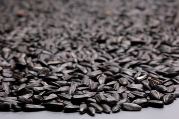 Obraz premium Pile of black sunflower seeds background with selective focus