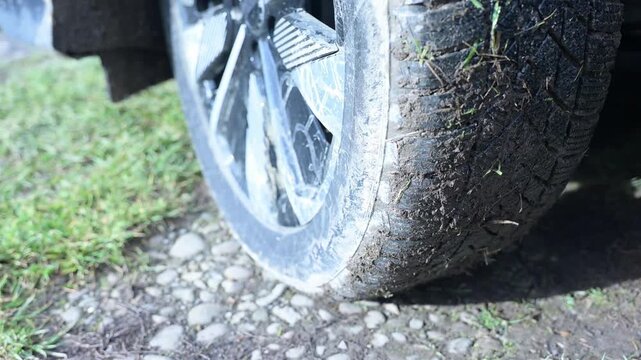 Rotation of the wheel of an electric car in place. A vehicle is stranded on a muddy trail with a flat tire under bright sunlight