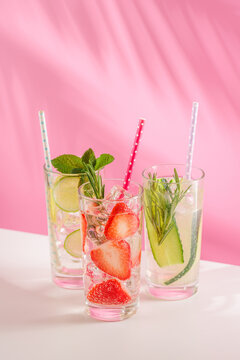 Set of fresh non alcoholic drinks with strawberry cucumber and lemon on pink background