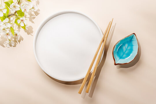 Empty white plate with chopsticks and blue bowl