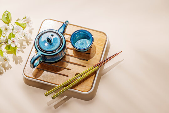Blue teapot with blossom branch on wooden tray