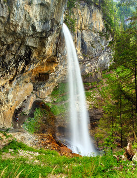 Johannes Waterfall cascades beautifully down rocky cliffs in Obertauern. Towering trees surround the area, creating a serene environment perfect for nature lovers and hikers seeking adventure.