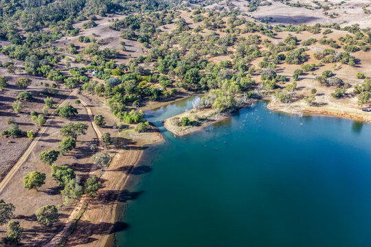 Aerial view of Glenbawn Dam and camping areas along the shoreline with low clouds surrounding the mountain landscape in NSW Australia. Drone photograph captures the expansive reservoir