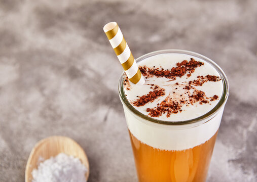 Fashionable food and drink glass of iced oolong tea with a layer of cream cheese foam with cocoa powder, a traditional Chinese drink on a gray background. Selective focus. Close-up.Copy space.