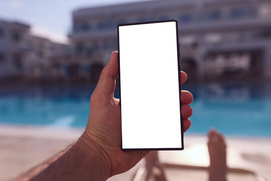 Woman relaxing by swimming pool while using smartphone with blank white screen mockup.